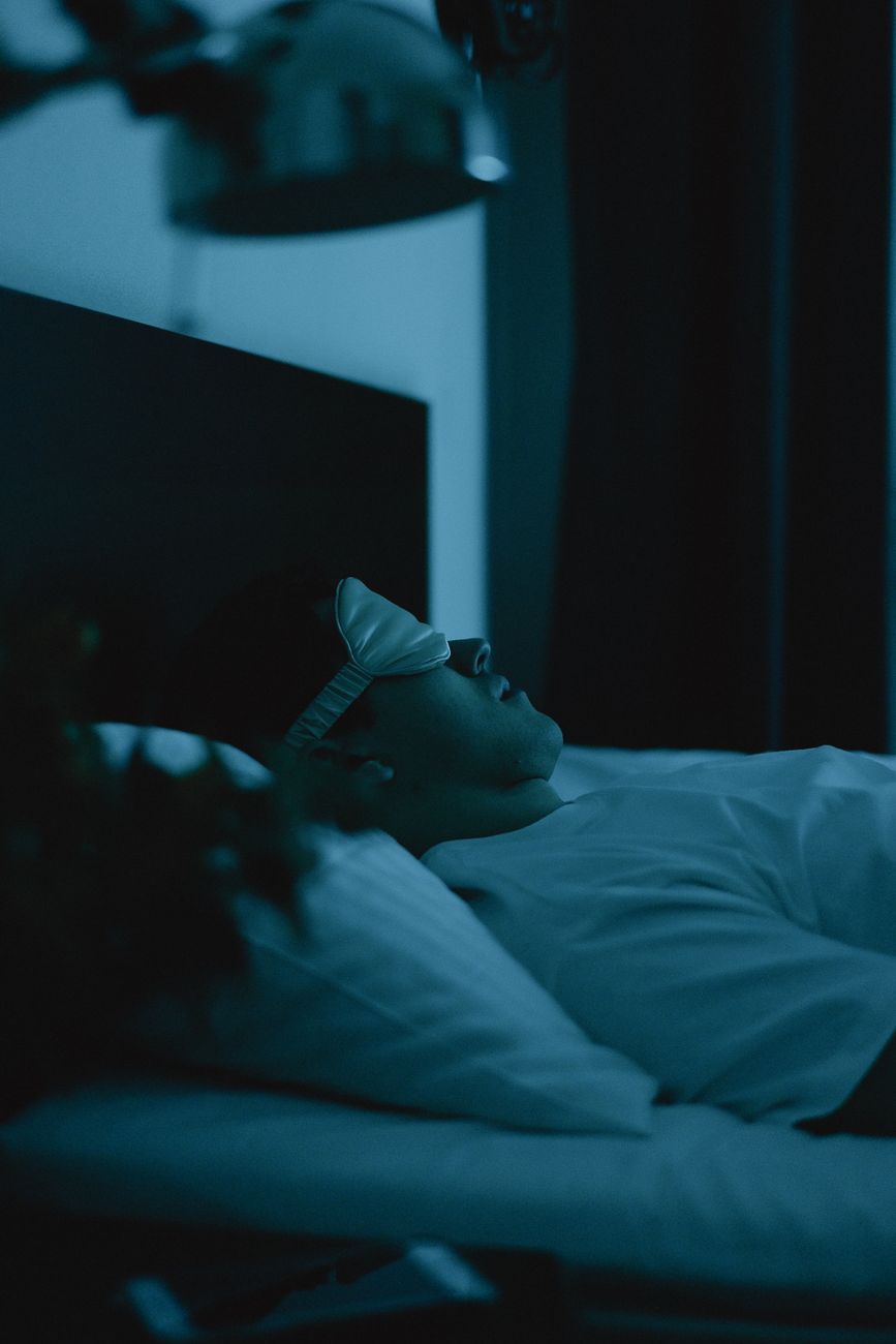 man wearing a sleep mask lying on bed